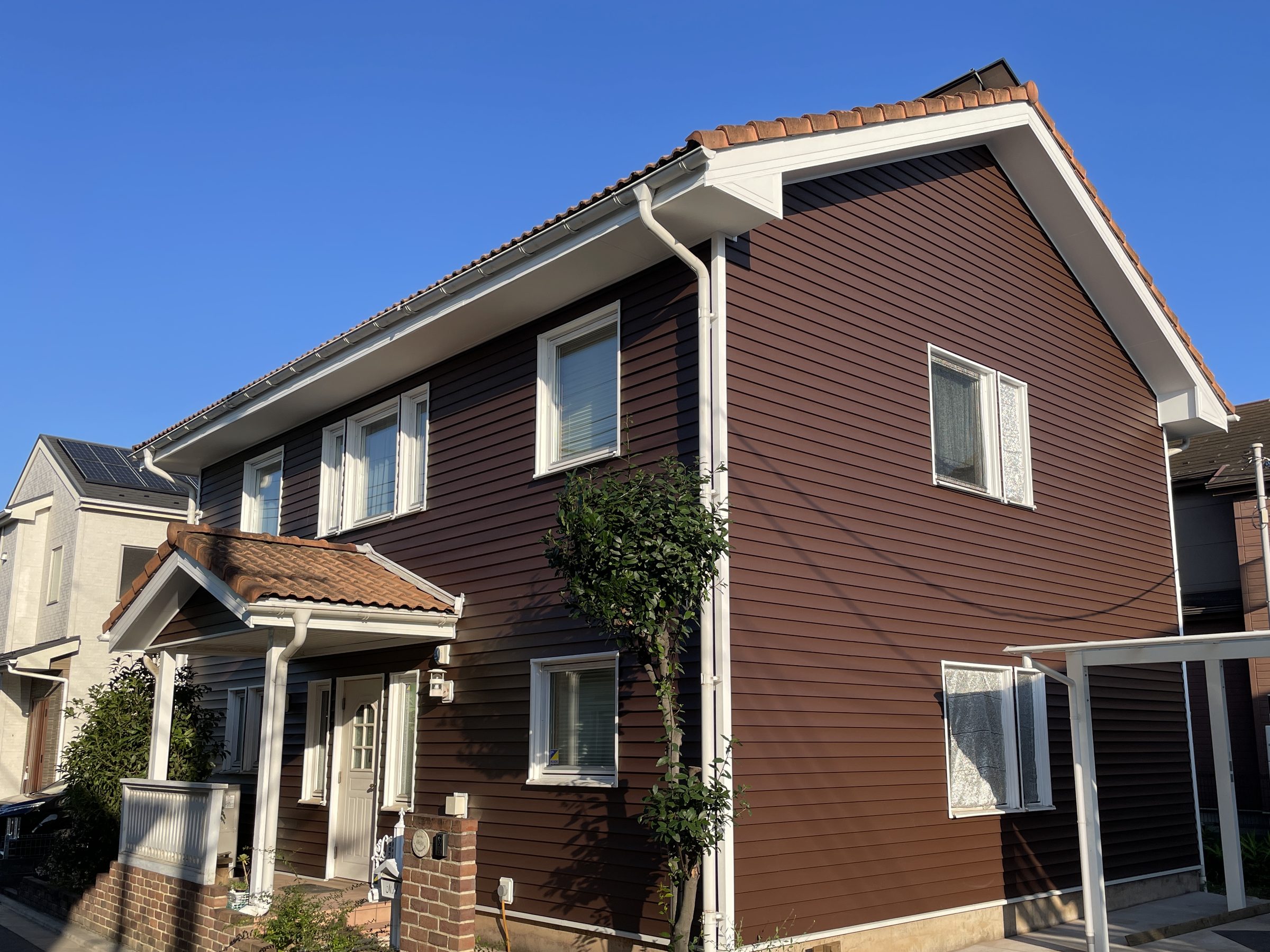 茶色の樹脂サイディングと白い枠で仕上げた住宅の外観